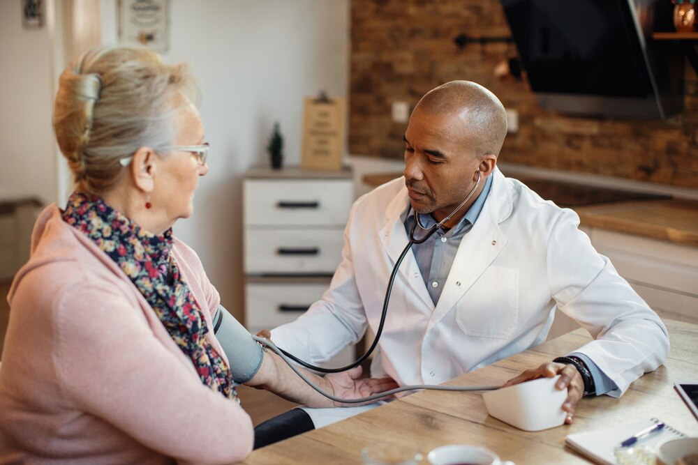 Black doctor measuring senior woman's blood pressure during home visit